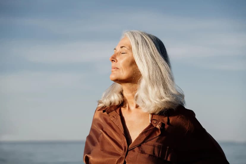 Calm woman with grey and white hair standing in the sunrise